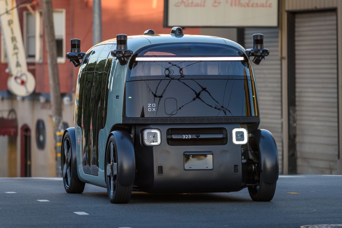 A boxy purpose-built robotaxi with no steering wheel on a city street